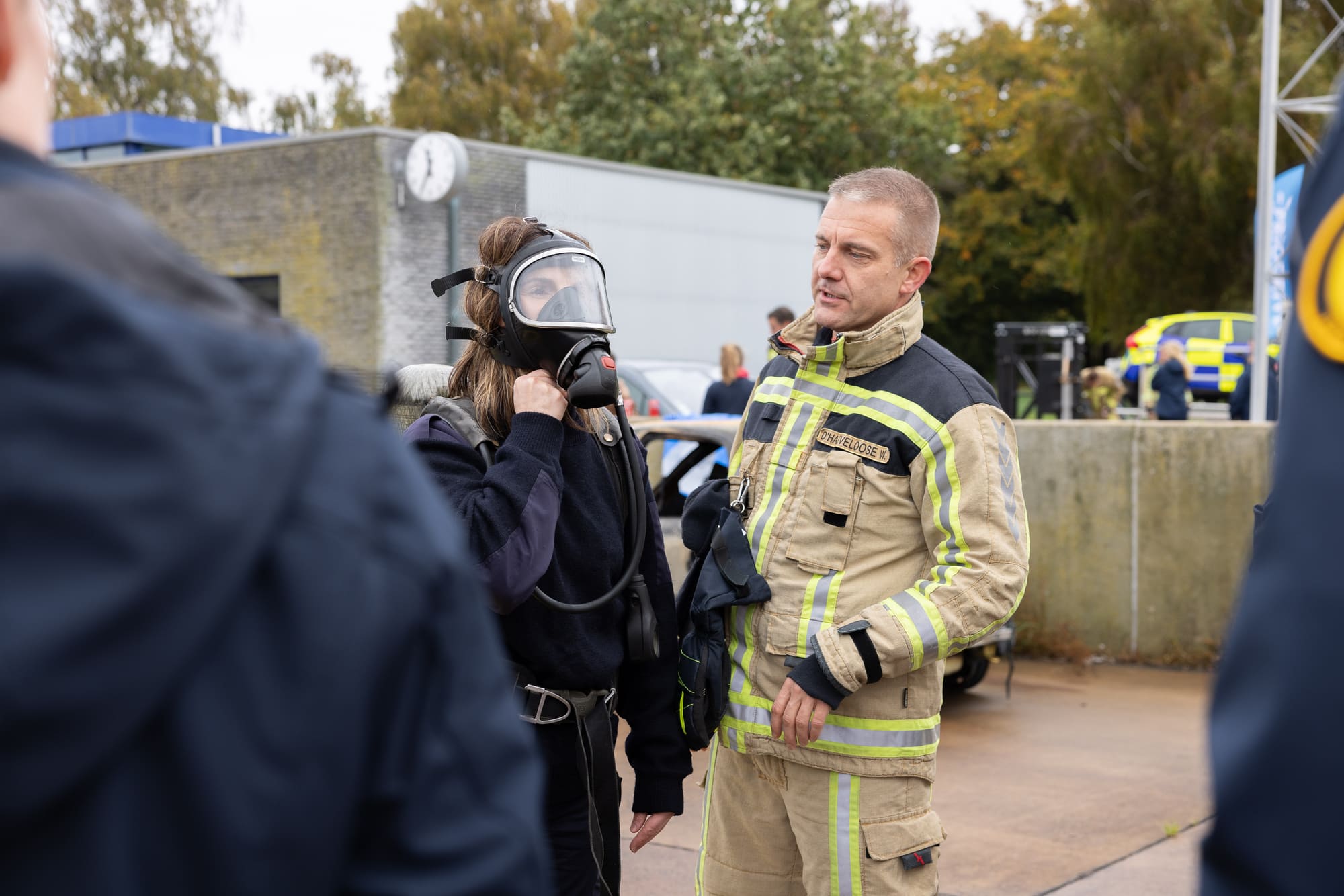 Deelneemster past een ademluchtmasker onder begeleiding van een instructeur