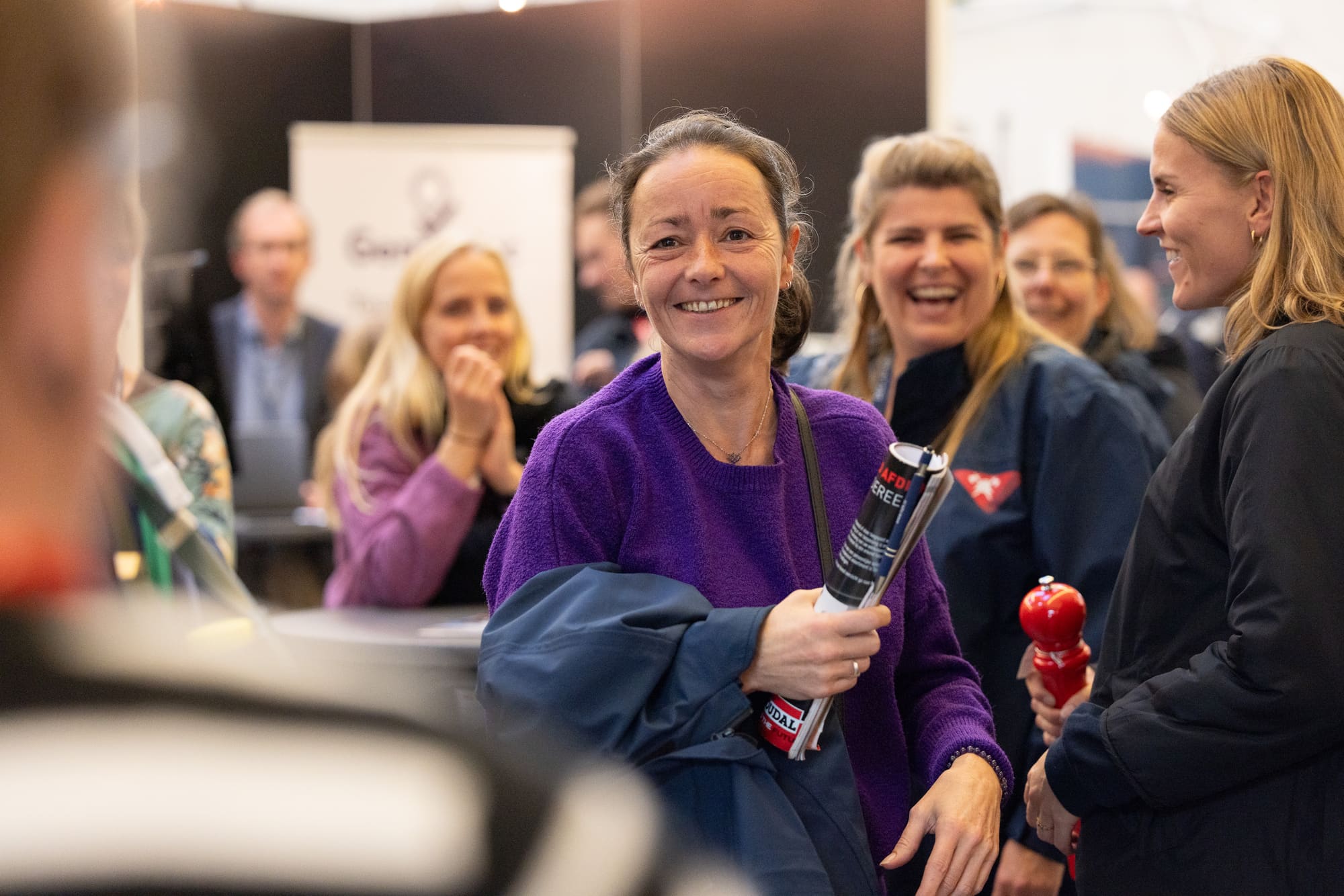 Lachende deelnemers in gesprek op de beursvloer van het congres